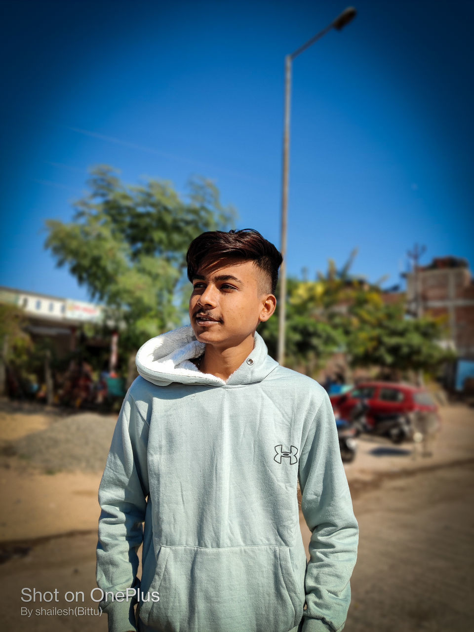 one person, sky, city, standing, blue, street, young adult, men, adult, waist up, architecture, casual clothing, nature, looking, emotion, clothing, tree, front view, day, lifestyles, spring, portrait, outdoors, person, focus on foreground, looking away, happiness, clear sky, city life, smiling, building exterior, road, copy space