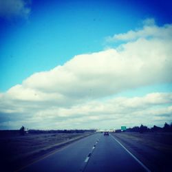Country road against cloudy sky