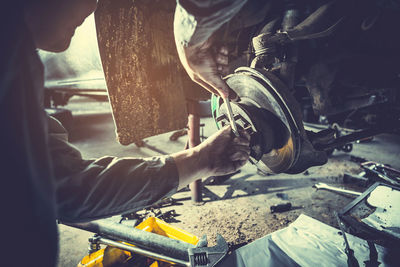 Cropped hands of mechanic repairing engine in workshop