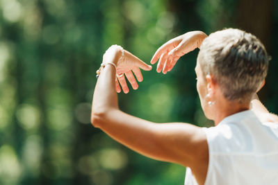 Mature woman doing tai chi exercises in the park. close up on hands position