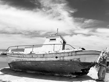 Abandoned boat moored at sea against sky