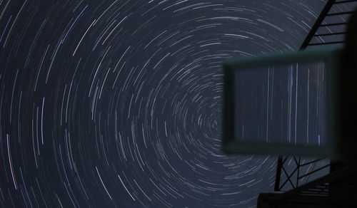Low angle view of light trails against sky at night