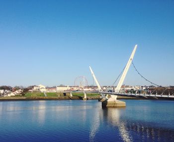 Bridge over river against clear blue sky