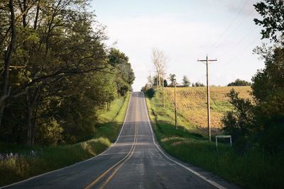 Road amidst trees against sky