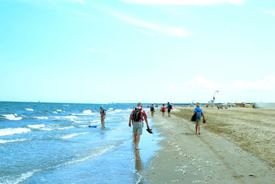 People walking on beach against sky