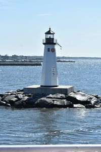 Lighthouse by sea against sky