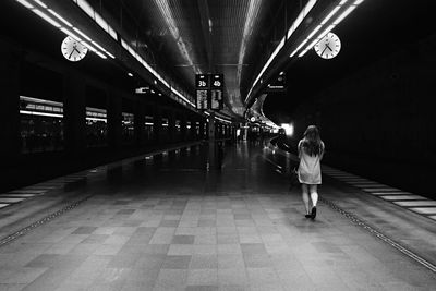 Rear view of woman walking on illuminated corridor