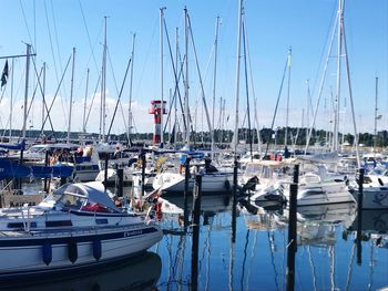 Sailboats moored at harbor against clear blue sky