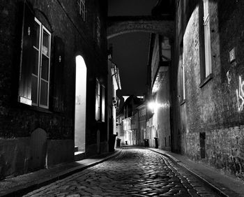 Empty alley amidst buildings at night