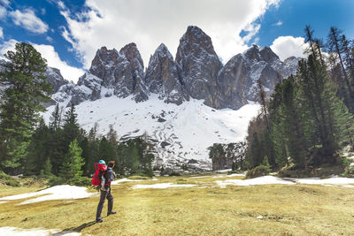 Woman walking on snowcapped mountains against sky