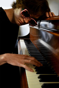 Midsection of man playing piano with glasses