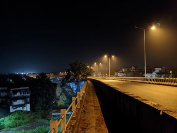 Illuminated street against sky at night