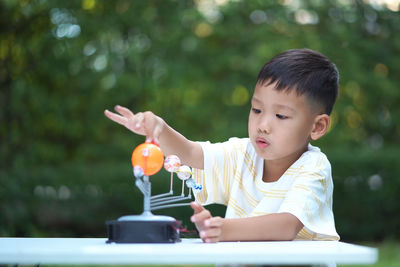 Close-up of cute boy playing with model on table in park