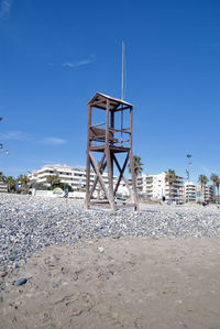 Lifeguard tower on field against clear blue sky