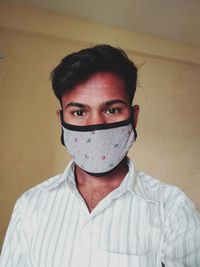 Portrait of young man covering face against wall