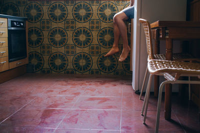 Low section of person sitting in cabinet at home