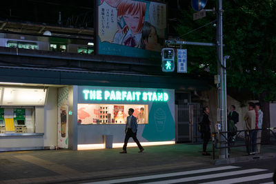 Full length of man walking on illuminated city street