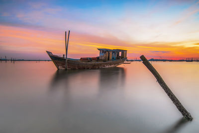 Ship moored on sea against sky during sunset