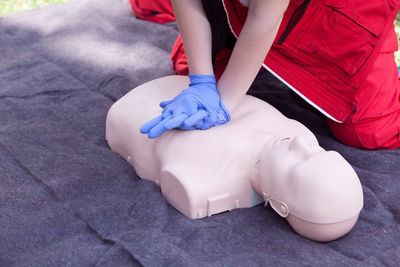 Midsection of person pressing mannequin man chest on grass field