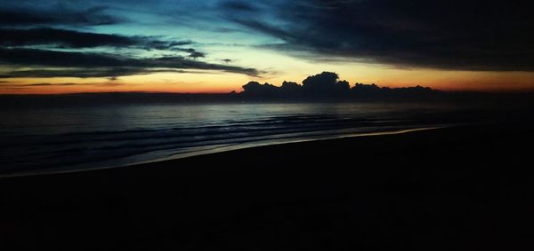 Scenic view of sea against dramatic sky during sunset