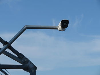 Low angle view of security camera against blue sky