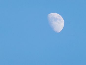 Low angle view of moon against clear blue sky