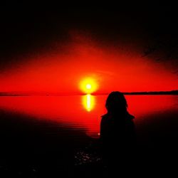 Silhouette of man in sea at sunset