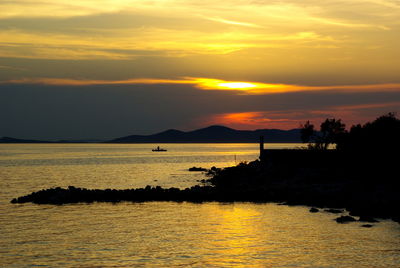 Scenic view of sea against dramatic sky during sunset