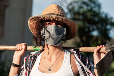 Portrait of woman wearing mask and hat standing with equipment