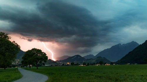 Scenic view of landscape and mountains against storm clouds