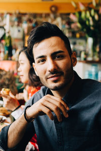 Portrait of confident young man sitting at table in restaurant during dinner party