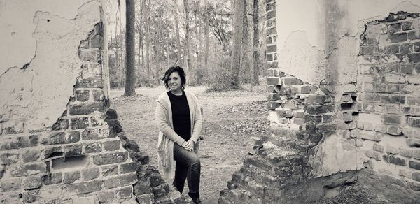 Portrait of young woman standing against building