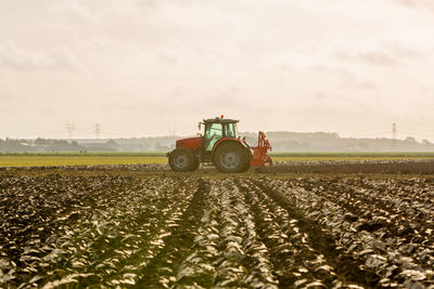 Tractor on agricultural field against sky