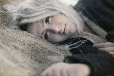 Surface level of thoughtful woman lying on sand at beach