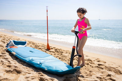 Little girl inflating a paddle surf on the beach
