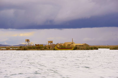 Nautical vessel on sea by buildings against sky