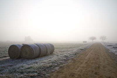 Hay bales on field against clear sky