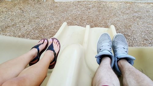 Low section of friends sitting on slide at playground