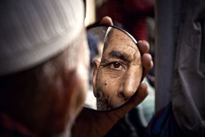 Close-up of man holding mirror with reflection