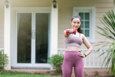 Portrait of smiling woman standing against house