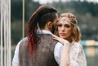 A loving married couple the bride and groom in suits celebrate wedding near the mountains and water