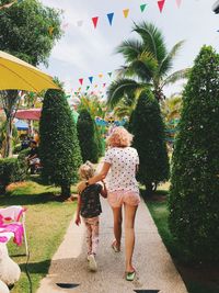 Rear view of women walking in park against sky