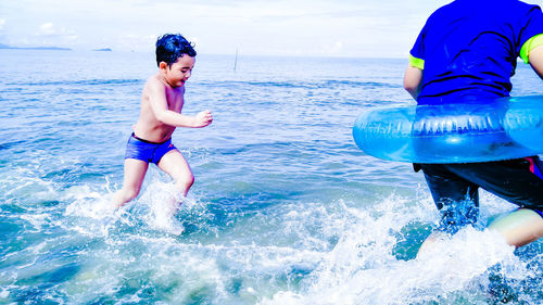 Shirtless playful boy with brother in sea