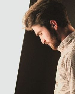 Portrait of young man looking away against white background