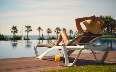 Woman relaxing in swimming pool at beach against sky