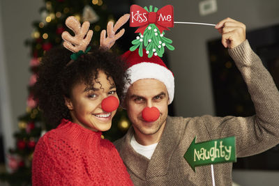 Portrait of couple wearing clowns nose during christmas at home