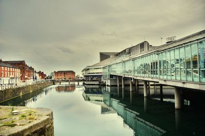 Bridge over river by buildings against sky