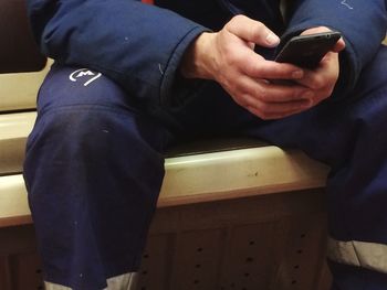 Midsection of man holding mobile phone