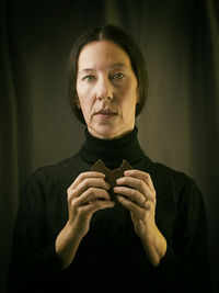 Woman dressed in black with chocolate in her hand in a romantic attitude ii