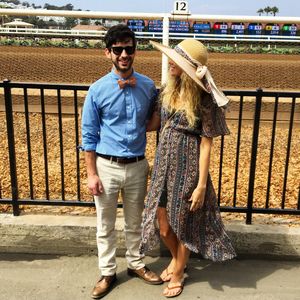 Smiling friends standing against horseracing track